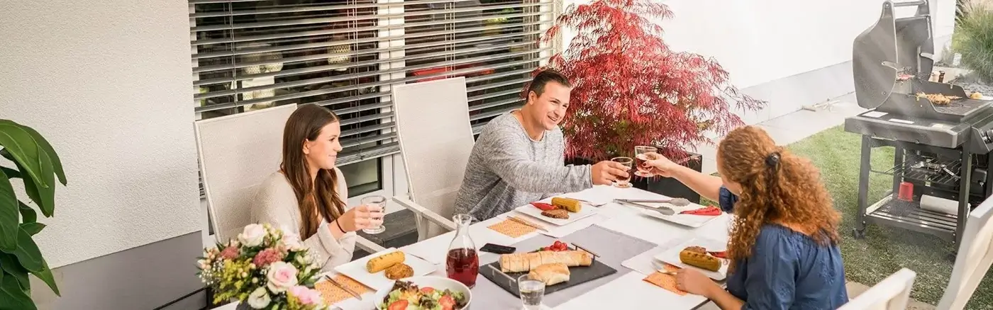 Familie sitzt beim Brunch daußen unter ihrer Markise